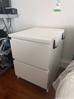 Front and side view of the white laminated side table with two drawers.