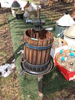 Front view of grape press showing wooden slat barrel, metal hoops, base