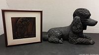 Side view of the black hand cast poodle figurine and framed copper embossed plate showing details and condition