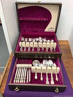 Full view of the closed wooden box with drawer containing the flatware set, lined in purple velvet.