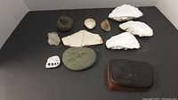 Display of all natural decor items including reclaimed oak wood box with lid, three large white seashells, a spiral fossil, and various stones including one with engraved dove.