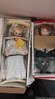 Two porcelain dolls in their original boxes with protective packaging and box padding.