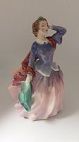 Front angle view of the Royal Doulton figurine showing the woman's face, upper body, dress, and green hat in hand.