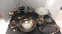 Full set of silver plate serveware arranged including coffee pot, goblets, candy dishes, and bowls