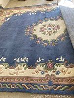 Overview of the full carpet showing the central medallion and border design in blue and cream with floral accents.