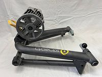 Side view of black CycleOps bike trainer with fan-style resistance unit and foldable metal frame on white background.