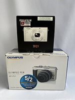 Two camera boxes: Fujifilm XQ1 box displayed behind Olympus PEN E-PL1 box