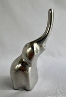 Front view of the polished aluminum elephant sculpture showing the smooth contours and raised trunk.