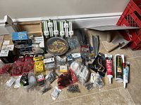 Wide view of repair items including light bulbs, anchors, screws, adhesive tubes, and hand tools.