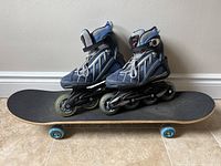 Pair of women's Rollerblade inline skates size 7 placed on top of Mongoose skateboard with blue wheels and black grip tape.