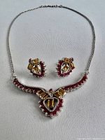 Full set photo showing necklace with heart-shaped pendant and matching earrings, highlighting the yellow-orange and red semi-precious stones and silver metal setting.