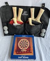 EastPoint table tennis paddles and balls in a black carrying case, with a boxed Pronto table top dart board in front.