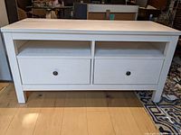 Front view of the white refinished IKEA Hemnes media unit showing two drawers and open shelves above.