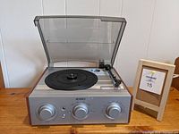 Front view of Jensen turntable with open clear dust cover showing controls and tonearm inside.