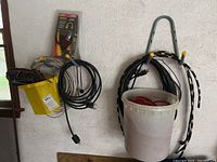 Photo showing various extension cords hanging on wall, bucket with cords, and packaged pig tail adapter