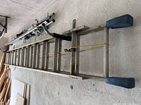 Full length view of 12 foot aluminum extension ladder with blue feet, showing surface wear and soiling.
