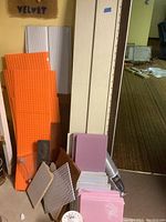 Full view of assorted foam boards, siding panels, metal mesh, dryer vent pipe and scrap pieces stacked together in basement area.