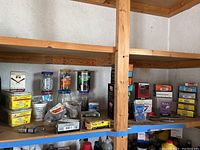 Full shelf view showing multiple boxes of nails, screws, staples and hooks in various packaging including yellow, blue, orange, and purple colors.