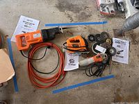 Photo showing the three power tools: reciprocating saw, orbital saw, angle grinder, plus manuals and multiple grinding discs.