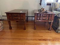 Front view of two matching wooden side tables showing the drawers and metal pulls, with visible scratches on the surface.
