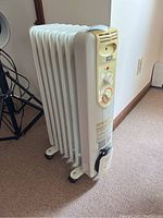 Full side view of the white oil-filled radiator space heater on caster wheels, showing its size and shape.