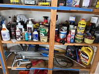 Shelf stocked with assorted vehicle fluids, cleaners, spray bottles, cans, and various maintenance products.