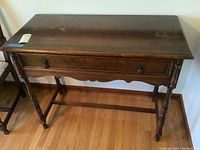 Overall view of the antique wood server showing top surface, drawer, turned legs, and stretcher support.