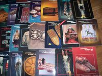 Covers of multiple issues of American Indian Art magazines spread on floor showing various Native American artworks and crafts like beadwork, pottery, and jewelry.