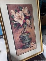 Framed floral art print showing a bouquet of white magnolia-like flowers with red berries in a green urn, framed in gold.