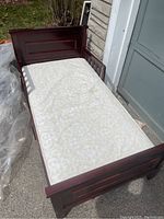 Full view of wooden child's bed frame with mattress showing general condition and style