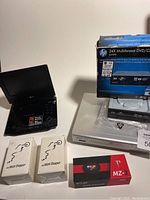 Photo of LG portable DVD player opened with screen visible beside HP 24X DVD/CD writer box and two white In-Watt Stopper devices in packaging plus two smaller boxed items.
