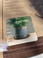 Box showing FabricPot brand, product information, small size, turquoise color, forest pattern, silo shape, and key features such as waterproof breathable fabric, decorative style, wide stable base, lightweight and durable, and innovative design.