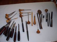 Set of vintage wooden-handled carving and graphic art tools arranged on a white surface