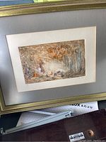 Framed abstract artwork showing the piece within a gray mat and gold frame, displayed at an angle with part of a label visible.