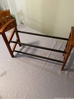 Photo showing wooden side panel and metal rods of the shoe rack, highlighting adjustable design and assembly screws.