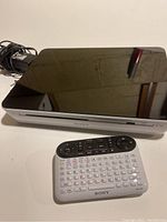 Sony NSZ-GT1 Blu-ray player with remote, showing the top and front of the player with remote placed in front.