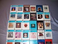 Front view of 32 vintage 8-track stereo tapes arranged in rows, showing album artwork and blue-bordered boxes, mostly in good condition from one collection, mostly club issues