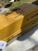 Side view of yellow plastic fishing tackle box labeled Plano, showing handle and lid.