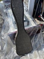 Full view of the vintage guitar case showing the exterior texture and shape, placed on a tarp outdoors.