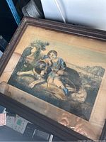 Full frontal image of the vintage framed print showing a boy and hunting dog in a natural outdoor setting enclosed in a dark wood frame.