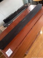 Visio black sound bar on wooden surface, showing full length and fabric cover.