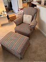 Armchair and ottoman with striped upholstery placed on carpet, with throw pillows on the armchair.