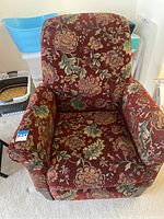 Front view of floral upholstered recliner chair with visible floral pattern and padded armrests