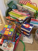 Stack of assorted gift bags and multiple bulk boxes containing blank greeting cards and wrapping accessories.