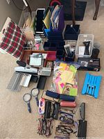 Photo showing a variety of office supplies including a plaid lap desk, file holders, pens, magnifying glasses, reading glasses, and other desk organizers.
