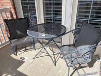 Patio table with two chairs showing entire set, chairs with cushions, placed on porch.