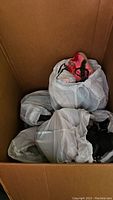 White drawstring bags containing assorted women's shoes, mostly boots and sneakers visible