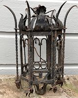 Front and side views of the wrought iron lantern showing detailed twisted bars, fleur-de-lis tops, and floral motif top.