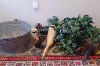 Full view of metal bucket, faux plant, four wooden ducks and one wooden bird arranged on floor