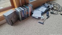 Photo showing assortment of DVDs and paperwork for Toshiba DVD player on carpeted floor near window.